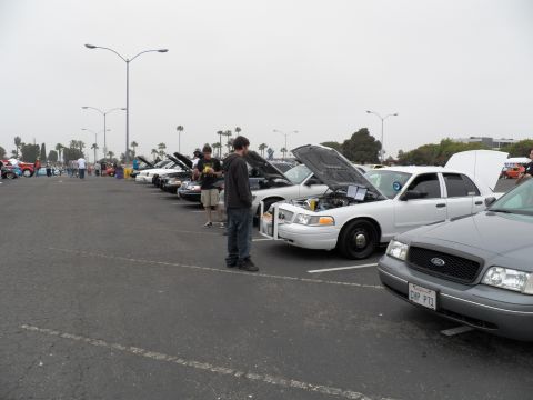 2003 Ford Crown Victoria - Long parking-lot lineup of hood-up Fords, foreground silver sedan plate reads CHP P71