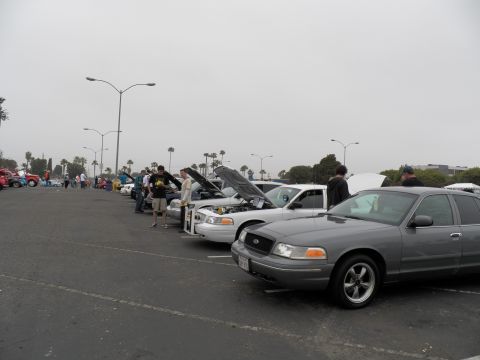 2003 Ford Crown Victoria - Gray Crown Victoria nearest camera with five-spoke wheels, more hood-up sedans and people up the row
