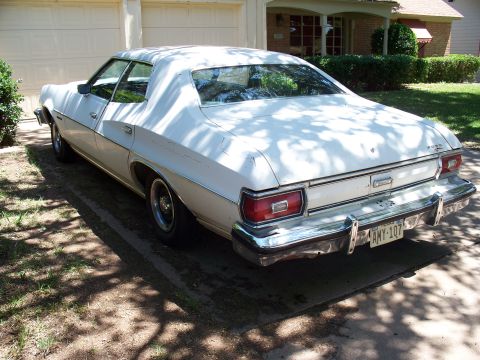 1976 Ford Torino - A white 1977 Ford sedan is parked in a driveway, showing its rear and side profile.