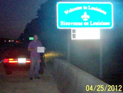 1984 Ford Mustang - Welcome to Louisiana sign at night with a person and car.