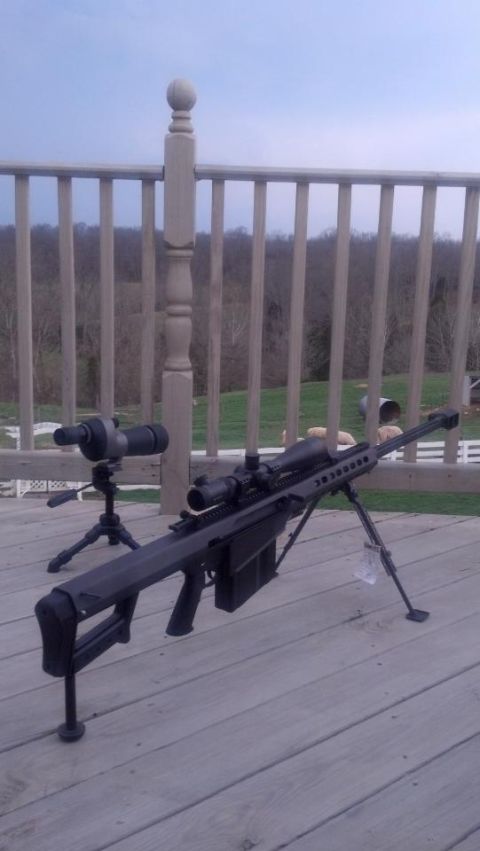 2000 Mercury Grand Marquis - A sniper rifle and spotting scope are set up on a wooden deck with a railing in the background.