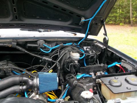 1989 Ford Bronco - The engine bay features custom blue wiring and an aftermarket air filter, obscuring specific year identification.