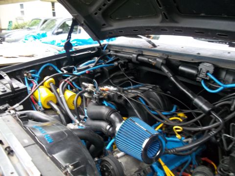1989 Ford Bronco - Engine bay modifications include blue hoses and an aftermarket air intake system.