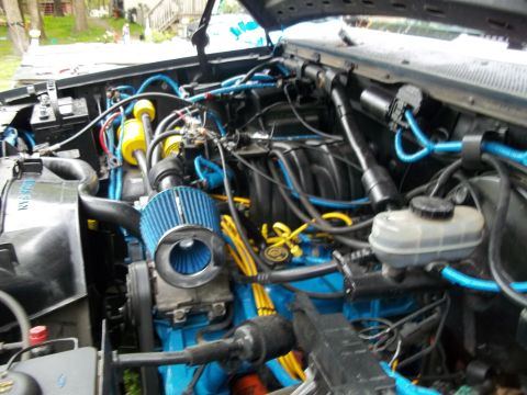 1989 Ford Bronco - The engine bay is filled with blue hoses and a blue air filter, with the engine block painted blue.