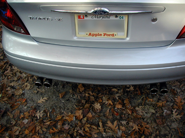 Silver Ford Taurus SE rear with Maryland plate frame and dual chrome exhaust tips under each bumper corner