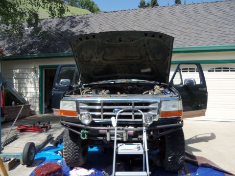 1968 Ford Bronco - A dark pickup truck is parked in a driveway with its hood and doors open, revealing the engine compartment.