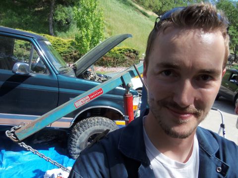 1968 Ford Bronco - A man poses with a green SUV that has its hood open and an engine hoist positioned over it.