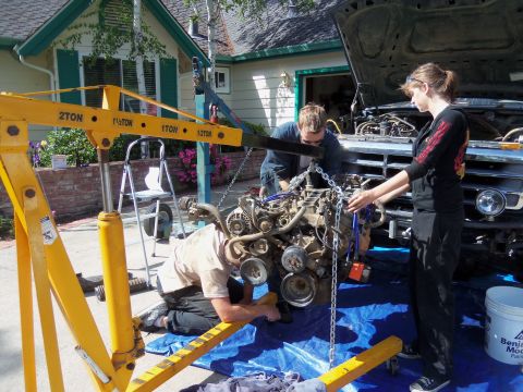 1968 Ford Bronco - Two people use an engine hoist to remove an engine from a truck.