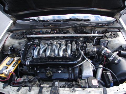 1992 Ford Taurus - The engine bay of a 1992 Ford Taurus SHO, its 24-valve DOHC engine and a yellow battery.