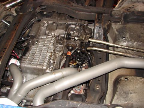 1992 Ford Taurus - Close-up of the transmission and exhaust system from underneath a vehicle, showing various mechanical components.