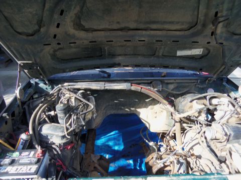 1968 Ford Bronco - The engine bay of a vehicle is shown with the hood open, revealing various engine parts and wiring harnesses.