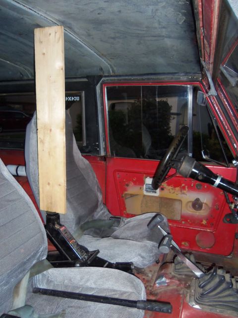 1968 Ford Bronco - Vehicle interior with a jack and wood block positioned near the driver's seat. The dashboard and shifter are visible.