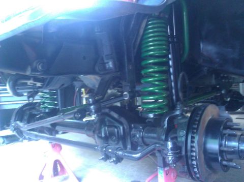 1979 Ford Bronco - Close-up view of a vehicle's suspension system, showing upgraded green coil springs and heavy-duty components.