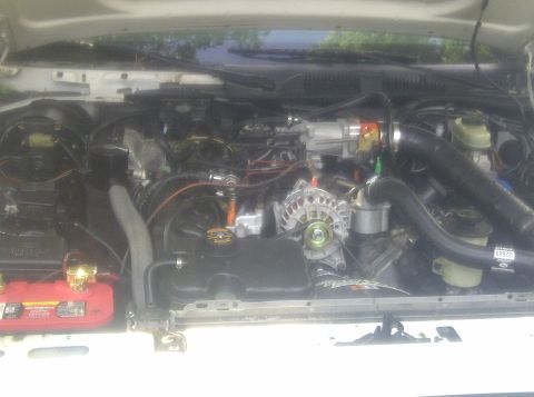 2000 Ford Crown Victoria - The engine bay of a white 2000 Ford Crown Victoria is shown, revealing various components.