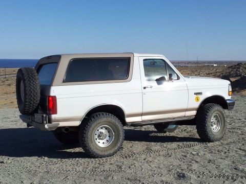 1996 Ford Bronco - This 1996 Ford Bronco is seen from a three-quarter front angle, parked outdoors on a dirt lot.