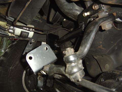 1986 Ford Bronco - Close-up of the steering linkage and suspension system components on a vehicle's underside.
