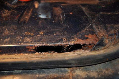 1986 Ford Bronco - A section of a vehicle's undercarriage shows significant rust and a large hole.