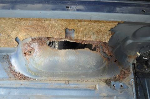 1986 Ford Bronco - Severe rust has eaten through this vehicle's interior panel, revealing a tire underneath.