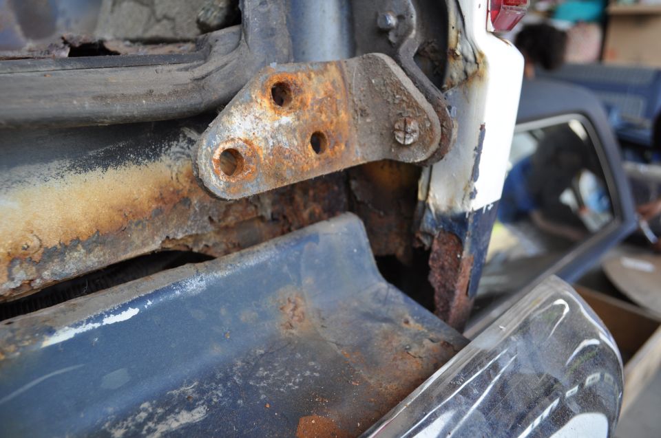 Rusted door hinge on a 1986 Ford Bronco, showing significant corrosion on the body panel