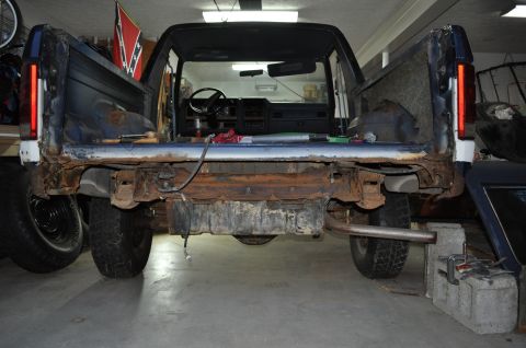 1986 Ford Bronco - Rear view of a 1986 Ford Bronco undergoing repairs, with significant rust visible on the chassis.