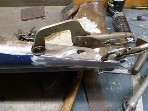 1969 MINI Cooper - A car body panel is being worked on, held in place by clamps, with various tools scattered around the workspace.