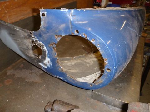 1969 MINI Cooper - A damaged blue fender with visible rust and holes sits on a workbench.