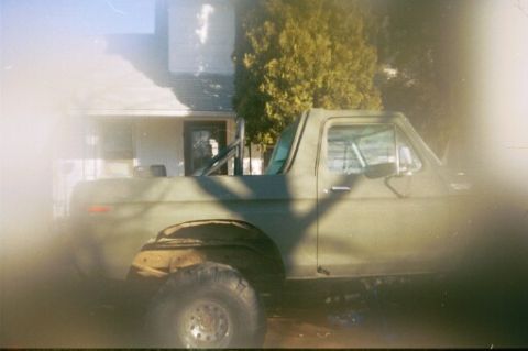 1979 Ford Bronco - This vintage Ford Bronco is seen from the side, parked near a residential building with trees in the background.