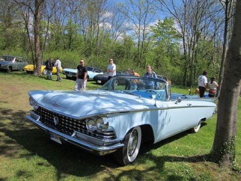 1991 Ford LTD Crown Victoria - A light blue 1959 Buick convertible is displayed at an outdoor car show with other vehicles and people in the background.