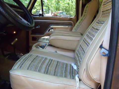 1979 Ford Bronco - The interior of a 1979 Ford Bronco features tan seats with a distinctive striped pattern and dual armrests.