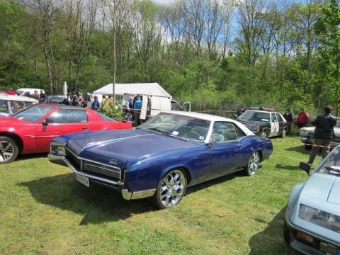 1991 Ford LTD Crown Victoria - A blue 1967 Buick Riviera coupe with a white roof is parked on grass at an outdoor event.