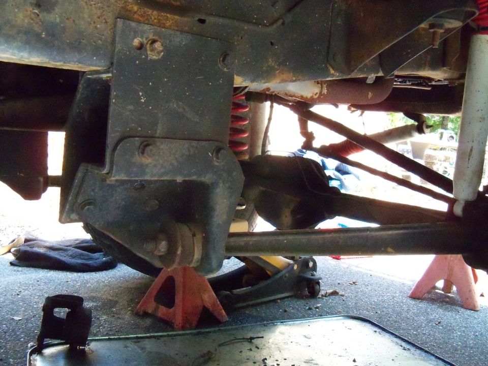Close-up of vehicle's rear axle, suspension springs, shocks, and frame supports on jack stands