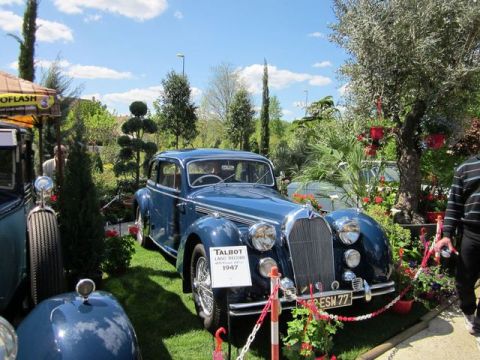 1991 Ford LTD Crown Victoria - A blue 1947 Talbot Lago Record sedan is displayed among lush greenery at an outdoor event.