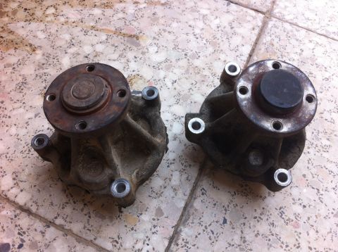 1998 Ford Crown Victoria - Two used water pumps are shown side-by-side on a tiled surface.
