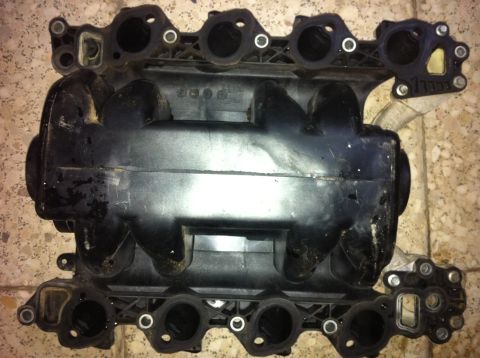 1998 Ford Crown Victoria - This is a black plastic engine intake manifold with multiple ports and visible part numbers stamped on it.