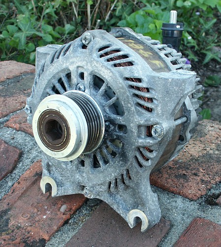 1998 Ford Crown Victoria - This alternator is shown with its pulley, resting on a brick surface.
