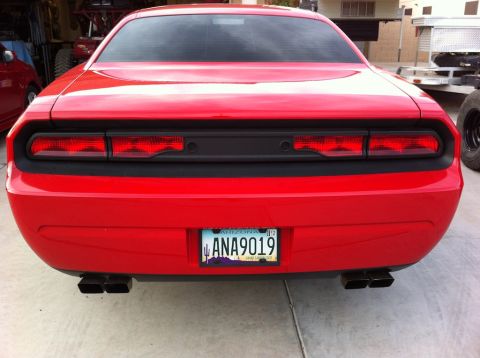 2010 Dodge Challenger - The rear of a red Dodge Challenger is shown, its distinctive taillights and dual exhaust pipes.