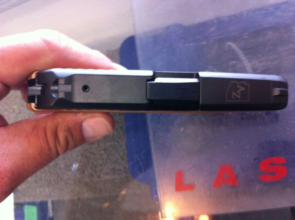 hand holding a black handgun with an AZ logo on the slide