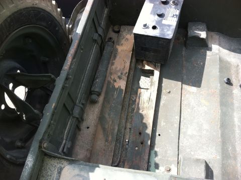 1986 Ford Bronco - The underside of a vehicle, showing the frame, a battery, and part of a tire and suspension.