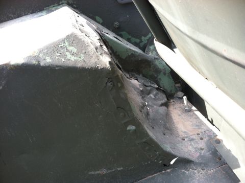 1986 Ford Bronco - Close-up view of the vehicle's undercarriage reveals areas of rust and chipped paint, suggesting wear and tear.