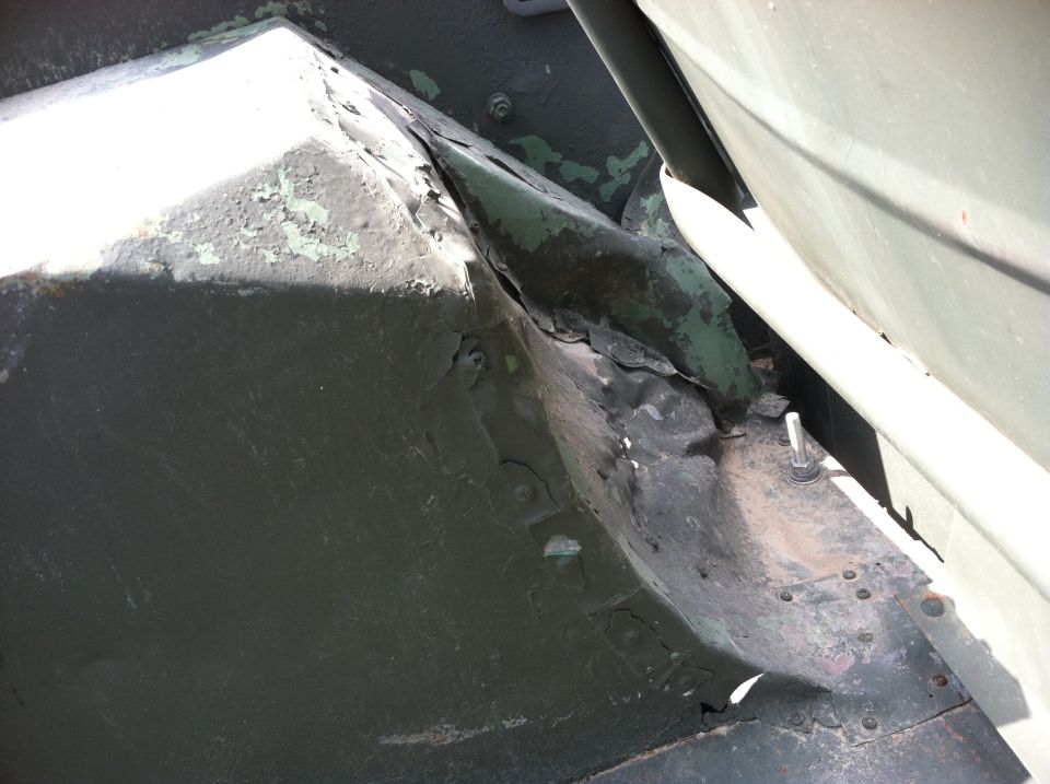 Undercarriage detail showing rust and peeling paint on a vehicle