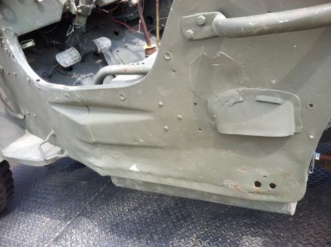 1986 Ford Bronco - Close-up view of the driver's side interior and exterior body panel of a military-style Jeep.