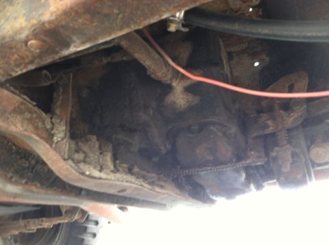 1986 Ford Bronco - Underside view of a heavily rusted vehicle chassis, showing various mechanical parts and frame components.