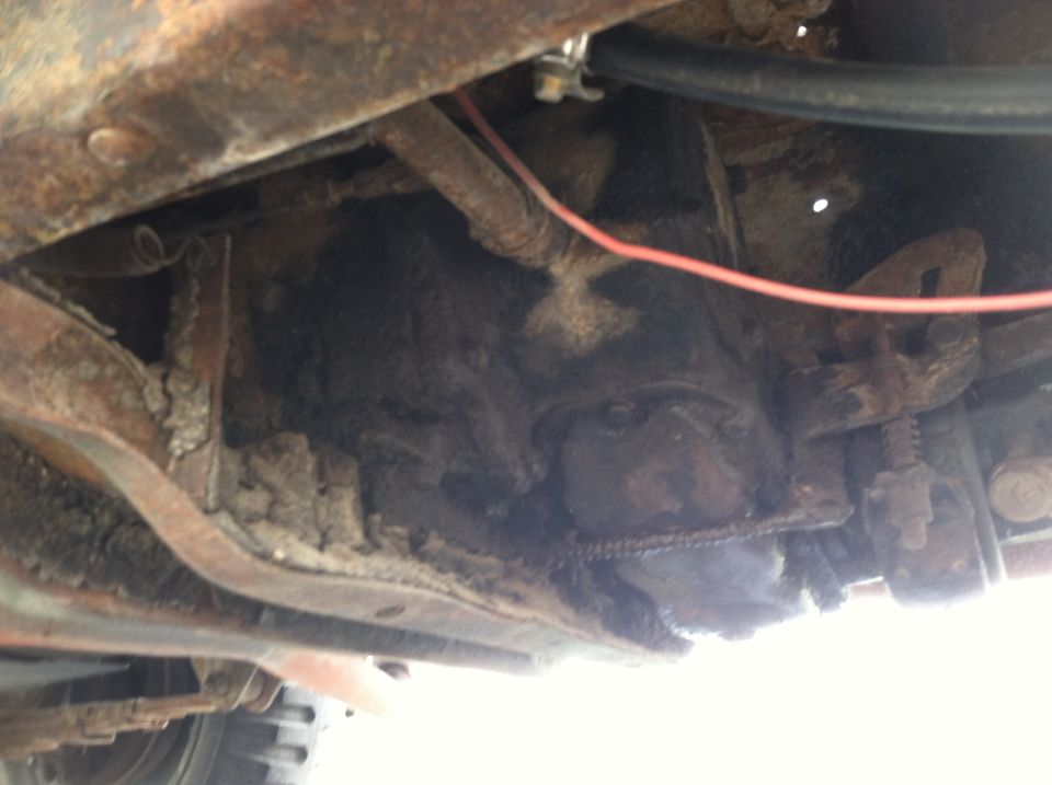 Close-up of rusty vehicle frame and undercarriage components, possibly a transmission or differential housing
