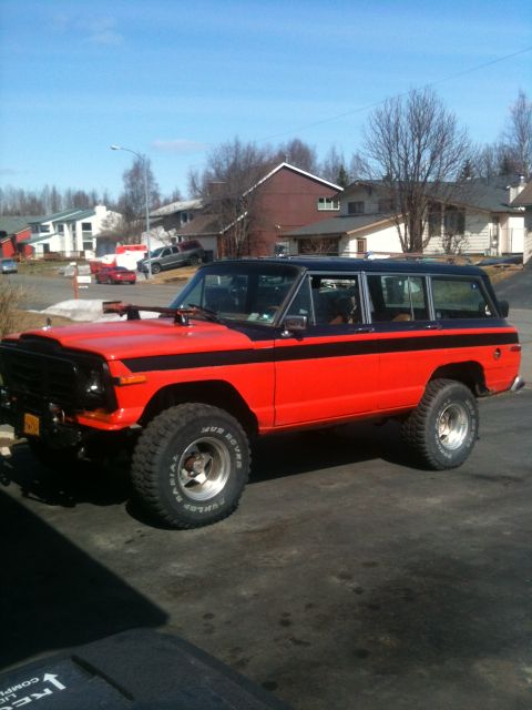 1990 Chevrolet Suburban - This Jeep Grand Wagoneer is painted red with black accents and has off-road tires.