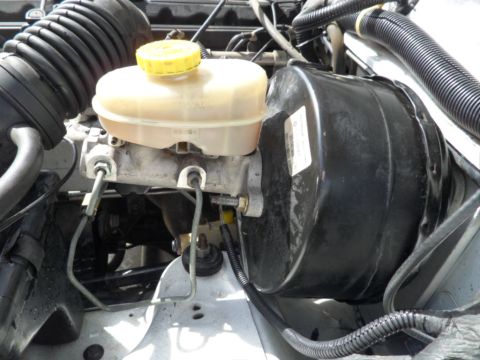 1994 Jeep Cherokee - Close-up of a vehicle's brake booster and master cylinder assembly.