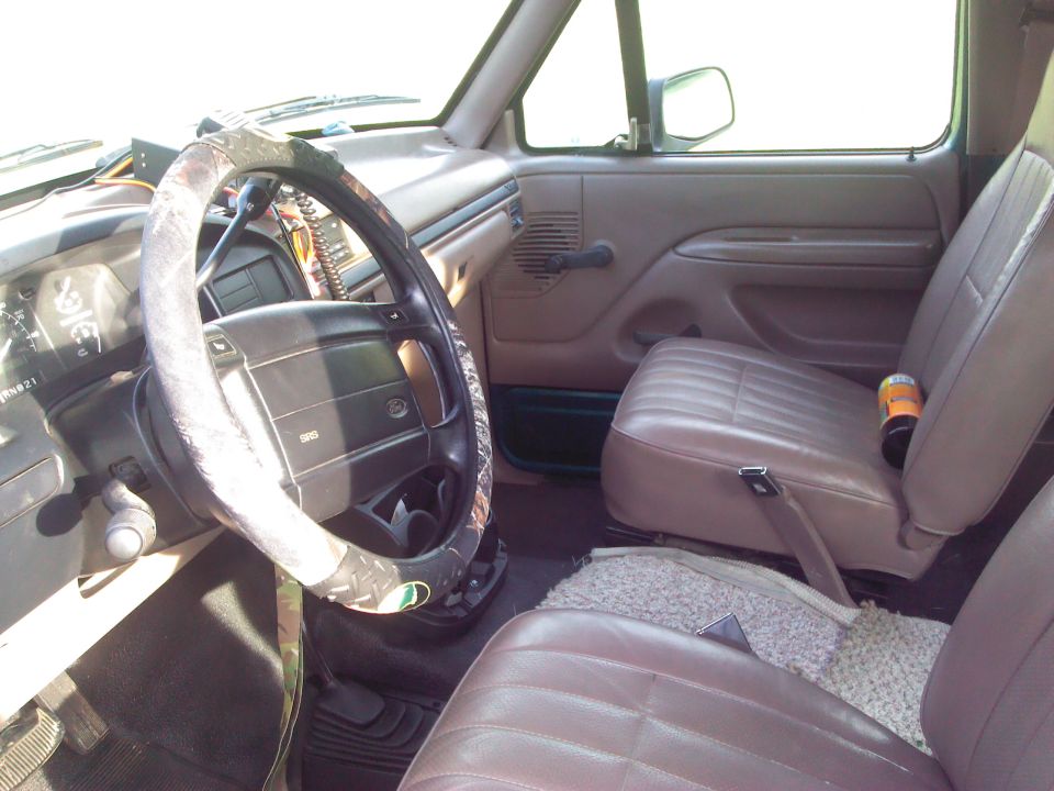 Brown leather seats and dashboard of a 1992 Ford Bronco, with a camouflage steering wheel cover