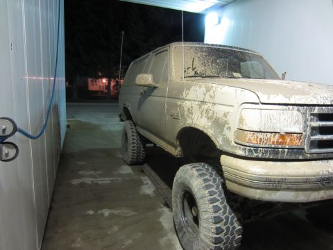 1992 Ford Bronco - Muddy 1992 Ford Bronco sits on a wash bay platform after off-roading.