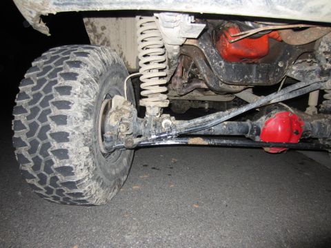 1992 Ford Bronco - The underside of a vehicle shows its suspension components and a large off-road tire.