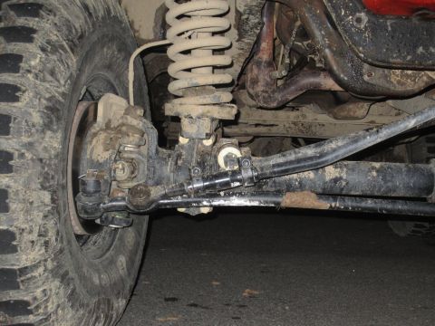 1992 Ford Bronco - Undercarriage view of a vehicle's front wheel, suspension, and steering linkage.