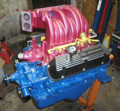 1988 Ford Bronco - A Ford Motorsport engine, painted pink and blue, is displayed on an engine stand.